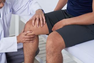 Orthopaedic doctor examining patient's knee during a doctor's visit